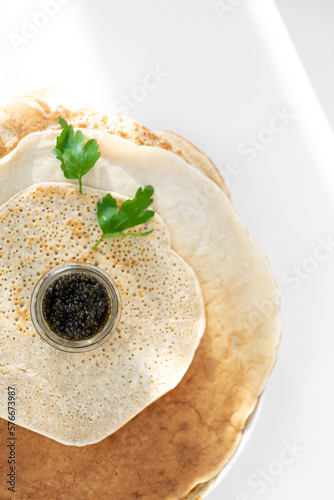 served pancake with black caviar, parsley