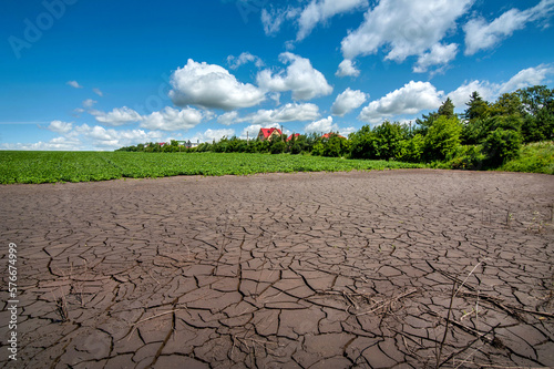 Cracked soil after flooding a field with green soybeans, drought near the village