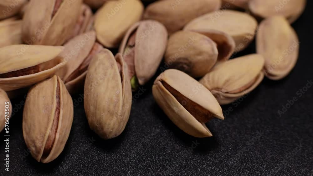 Salted pistachios, beer snack macro close-up rotate on a black background Salted pistachios, beer snack macro close-up rotate on a black background