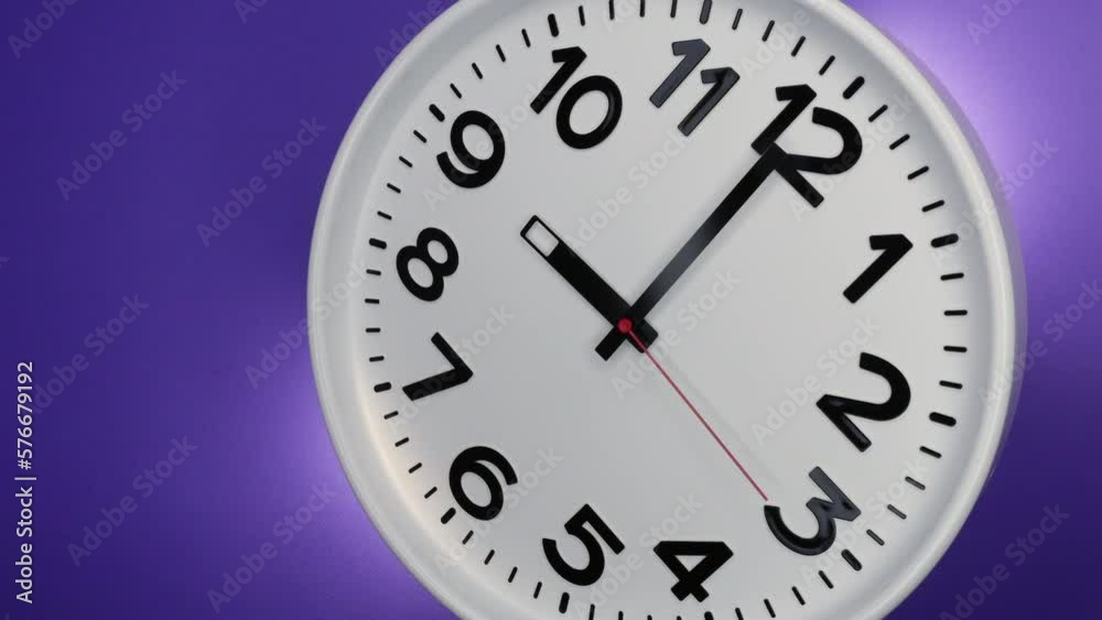 A White Wall Clock On Purple Background With A Time Of 9.00 Am Or Pm. A Black Hands and Red Second Hand Of The Clock. Timelapse. 4k. ProRes. A White Wall Clock On Purple Background With A Time Of 9.00 Am Or Pm. A Black Hands and Red Second Hand Of The Clock. Timelapse. 4k. ProRes.
