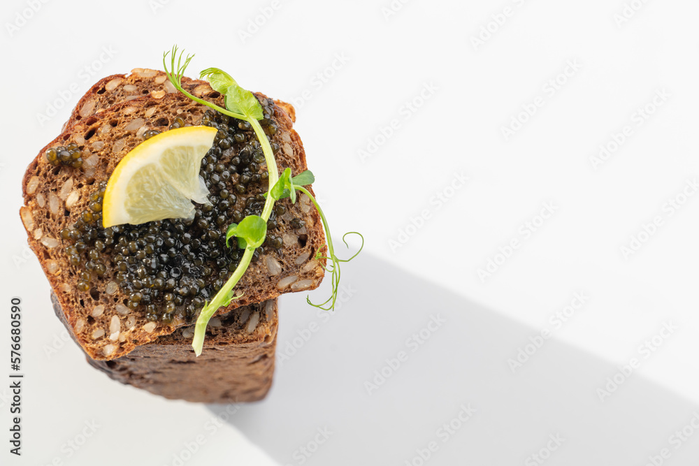 Black caviar on a sandwich with eggs, lemon, greenery