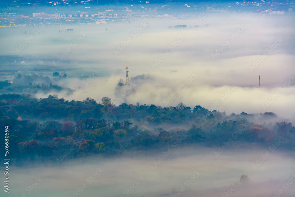 Aerial view of the town in the early morning mist is beautiful in the highlands. Low clouds and fog cover the sleeping city, photo in full moon light. Alpine mountain valley mists landscape at dawn