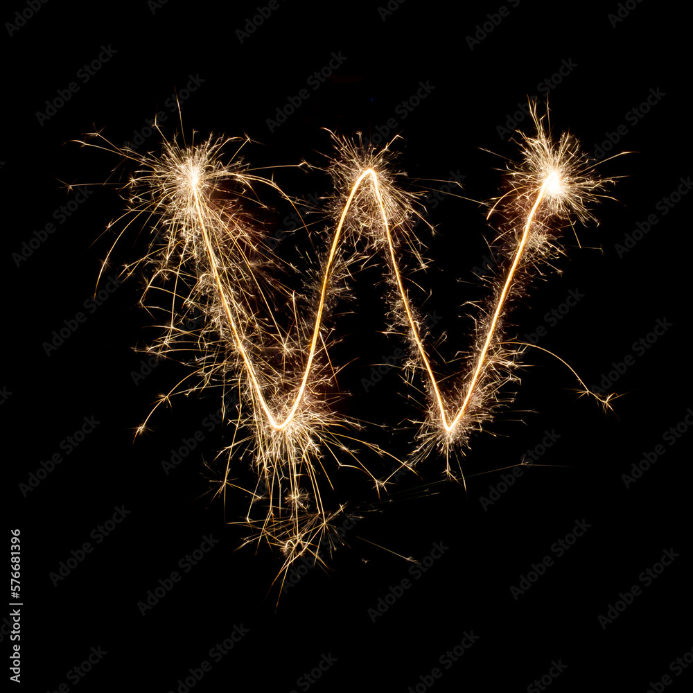 Sparkling burning creative letter W isolated on black background. Beautiful glowing golden overlay object for design holiday greeting card. Creative lettering W written with burning sparklers