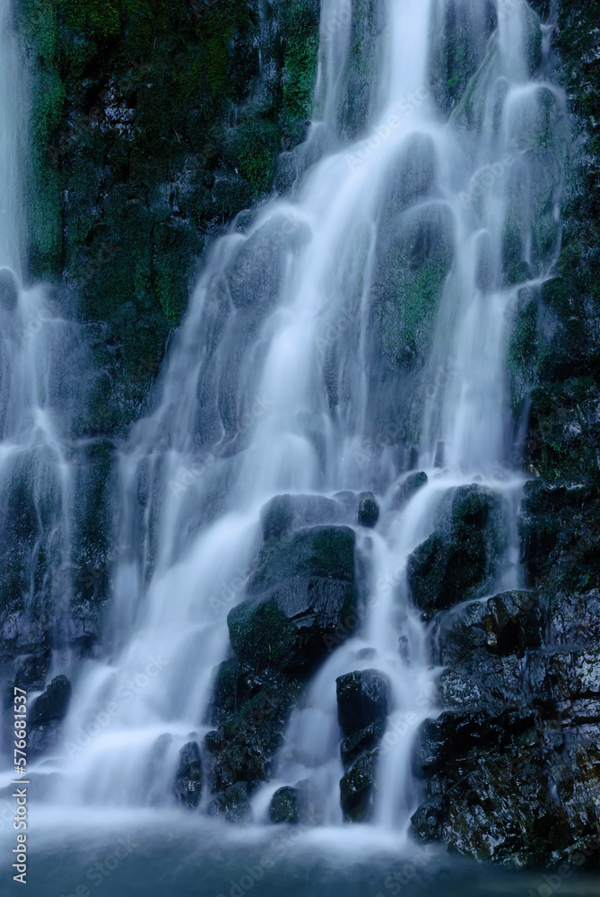 Beautiful mountain rainforest waterfall with fast flowing water and rocks, long exposure. Natural seasonal travel outdoor background with sun shining. Stream waterfall on rocks in the forest Beautiful mountain rainforest waterfall with fast flowing water and rocks, long exposure. Natural seasonal travel outdoor background with sun shining. Stream waterfall on rocks in the forest