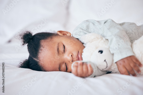 Black child, baby and sleeping with toy in bedroom, home and nursery for peace, calm nap and dreaming. Tired young girl kid asleep with teddy bear for resting, break and healthy childhood development photo