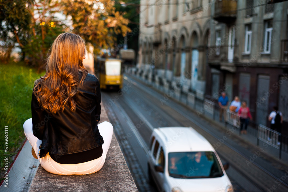 Fototapeta premium Smiling woman in the city street wearing black leather jacket and white pants and sunglasses