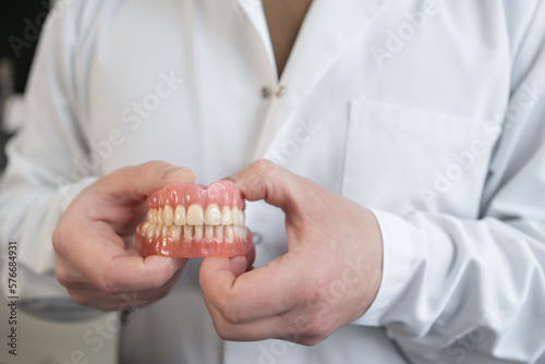 An orthopedic dentist holds dentures in his hands. Dentures in the hands of a doctor. Orthopedic dentistry. False teeth.