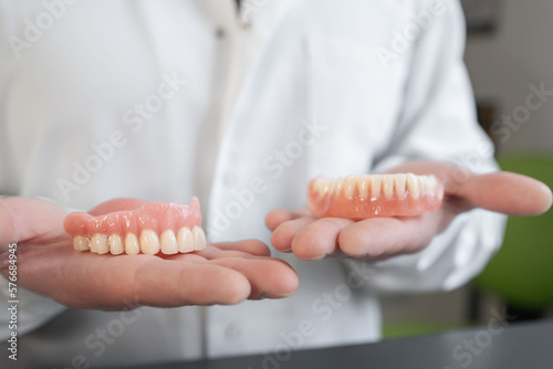 Dental prosthesis in the hands of the doctor close-up. Dentist holding ceramic dental bridge. Dental technician in lab. Prosthetic dentistry.  photo