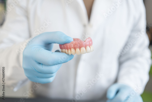 Dental prosthesis in the hands of the doctor close-up. Dentist holding ceramic dental bridge. Dental technician in lab. Prosthetic dentistry. 