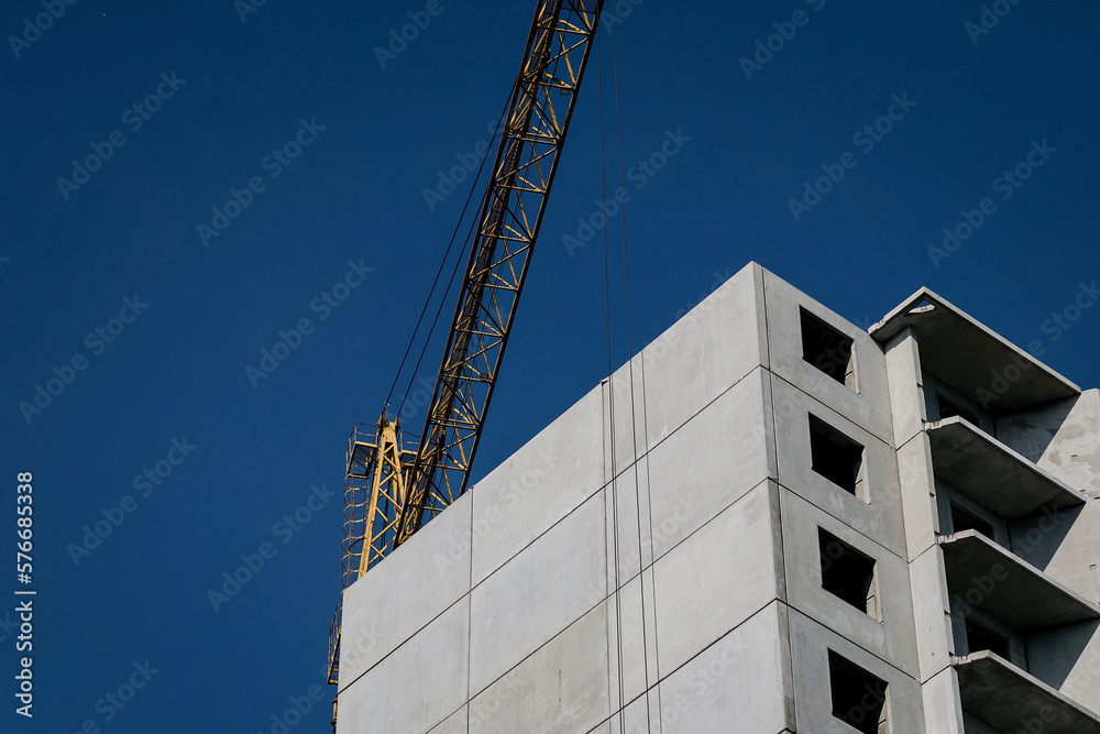Fototapeta premium Crane and building construction site against blue sky