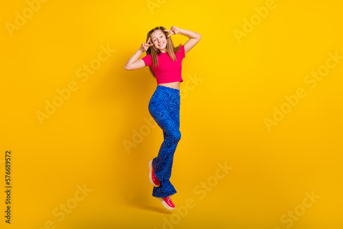 Photo of positive optimistic lady wear trendy clothes rejoice enjoy holiday weekend showing v-sign isolated on yellow color background