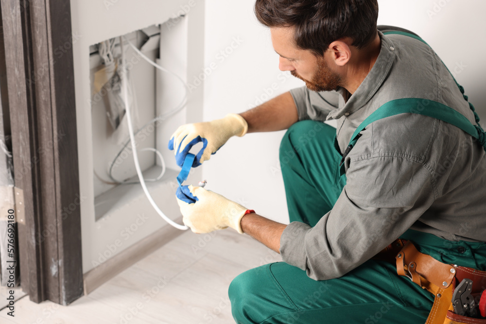 Electrician fixing wires with insulating tape indoors Electrician fixing wires with insulating tape indoors
