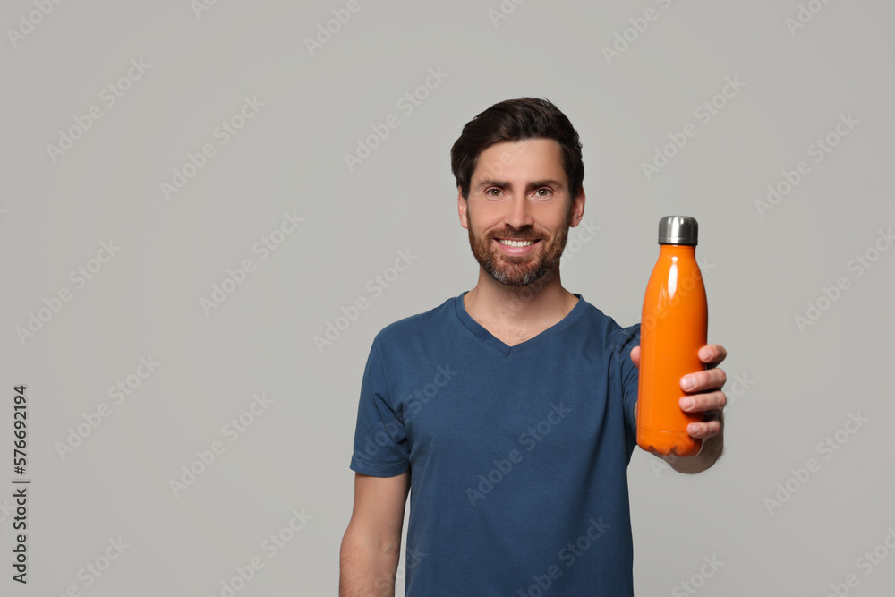 Man with orange thermo bottle on light grey background. Space for text Man with orange thermo bottle on light grey background. Space for text