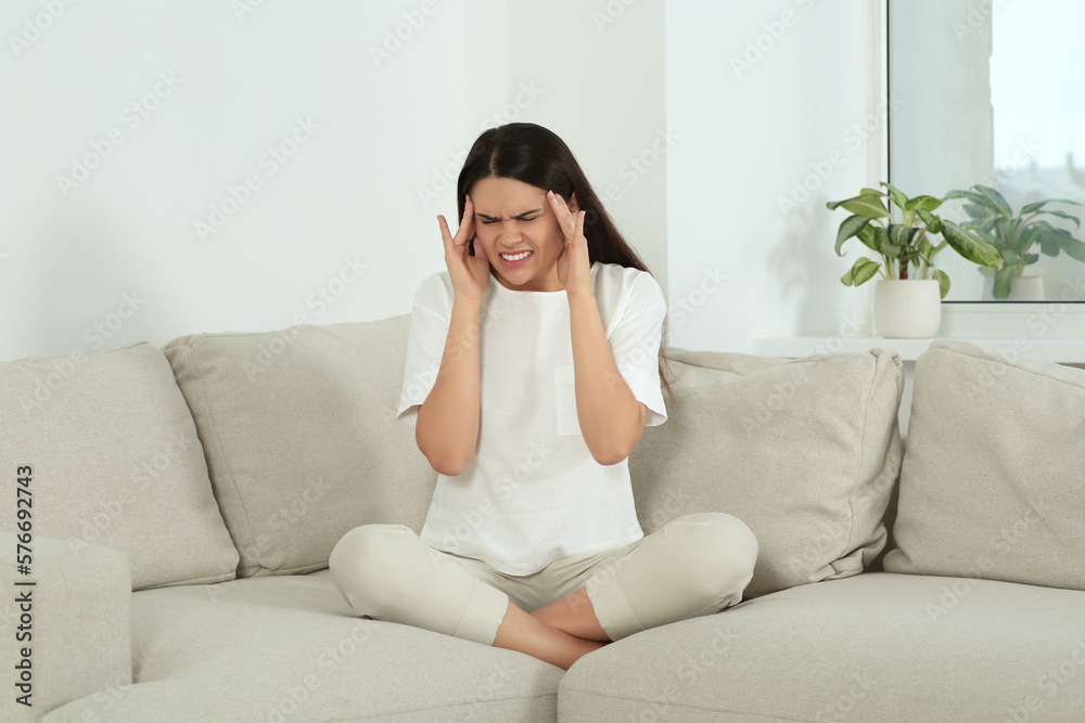 Young woman suffering from headache on sofa at home. Hormonal disorders Young woman suffering from headache on sofa at home. Hormonal disorders