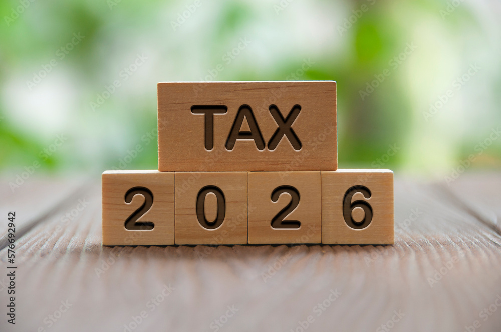 Tax 2026 text on wooded blocks with blurred nature background. Taxation and filing concept. Tax 2026 text on wooded blocks with blurred nature background. Taxation and filing concept.