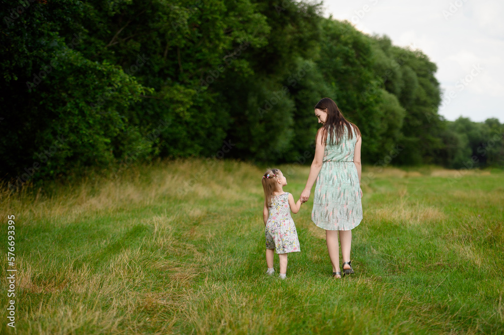 Fototapeta premium Portraits of joyful mother and daughter spend time together, enjoy happy family time, walk in the park. Mother's day.