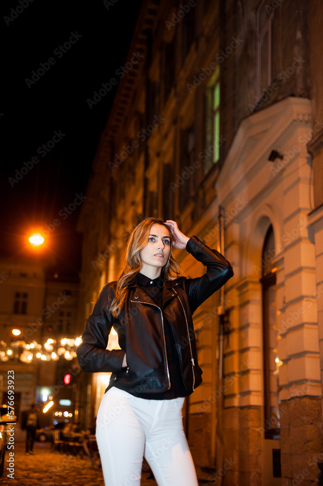 Beautiful smiling woman in leather black jacket in the night city.