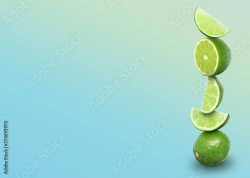 Stacked whole and cut limes on color background  space for text