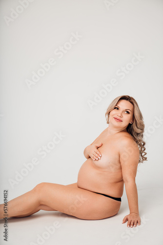 a naked pregnant against the background of a white cyclorama in a photo studio.  © andrey