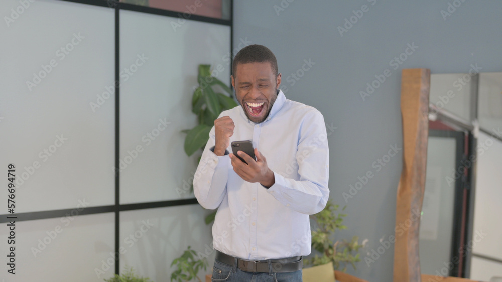 Excited African Man Celebrating Win on Smartphone