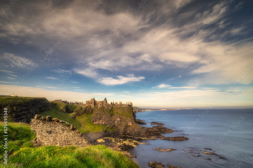 Ruins of Dunluce Castle located on the edge of cliff seen from behind of small wall, Bushmills, Northern Ireland. Filming location of popular TV show Game of Thrones