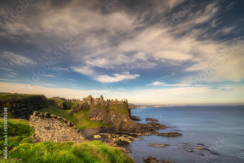 Ruins of Dunluce Castle located on the edge of cliff seen from behind of small wall, Bushmills, Northern Ireland. Filming location of popular TV show Game of Thrones