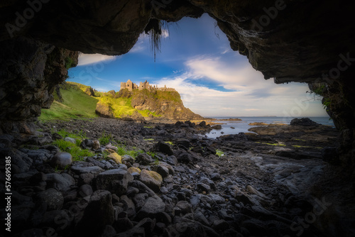 Φωτογραφία Dunluce Castle seen from a small cave on a shoreline, nested on the edge of clif