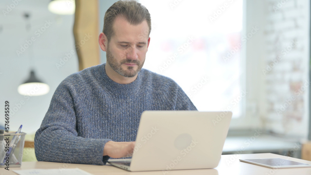 Middle Aged Man Typing on Laptop in Office Middle Aged Man Typing on Laptop in Office
