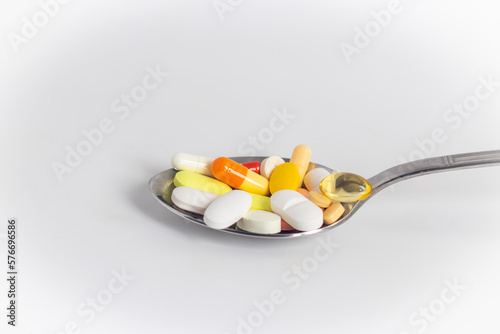 Medicines piled in a metal spoon standing on a white background. Stock photo. photo