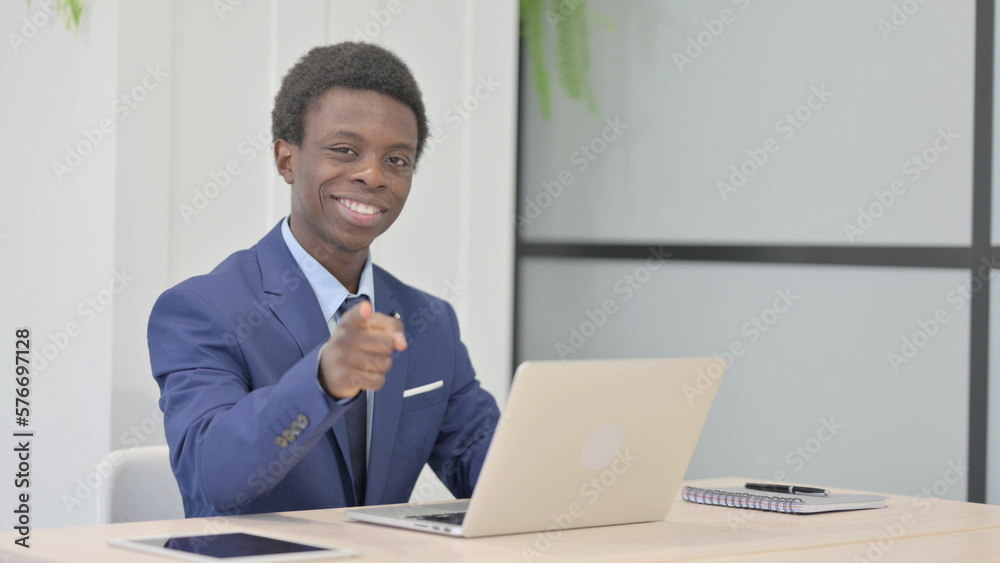 African Businessman Pointing at the Camera while Working on Laptop African Businessman Pointing at the Camera while Working on Laptop