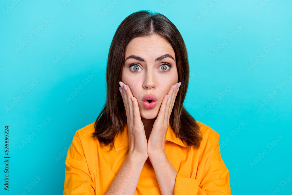 Photo of impressed funky woman dressed orange shirt big eyes arms cheeks isolated teal color background