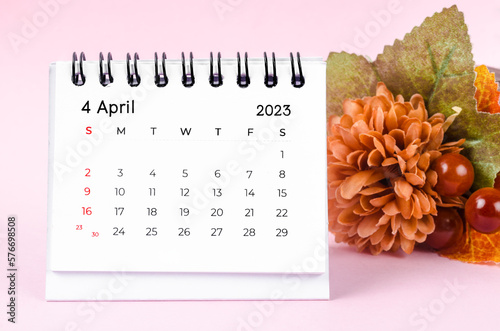 The April 2023 Desk calender with dried flower on pink background.
