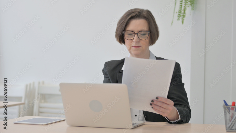 Old Businesswoman Working on Laptop and Documents Old Businesswoman Working on Laptop and Documents