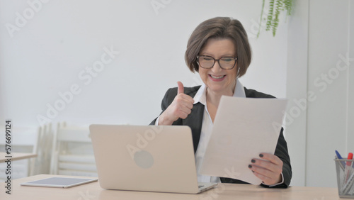 Old Businesswoman Celebrating Success while Doing Paperwork
