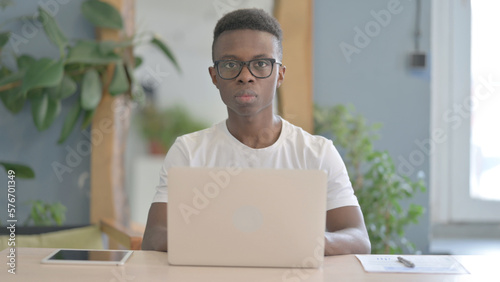 African Man Looking at Camera while using Laptop