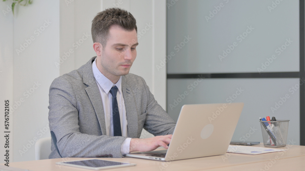 Young Businessman Typing on Laptop in Office Young Businessman Typing on Laptop in Office
