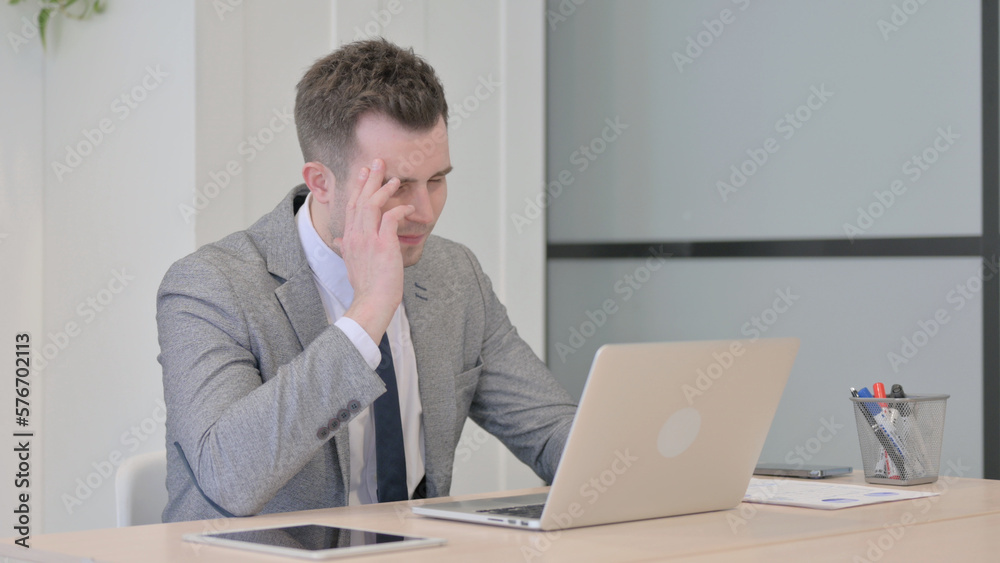 Young Businessman with Headache Working on Laptop
