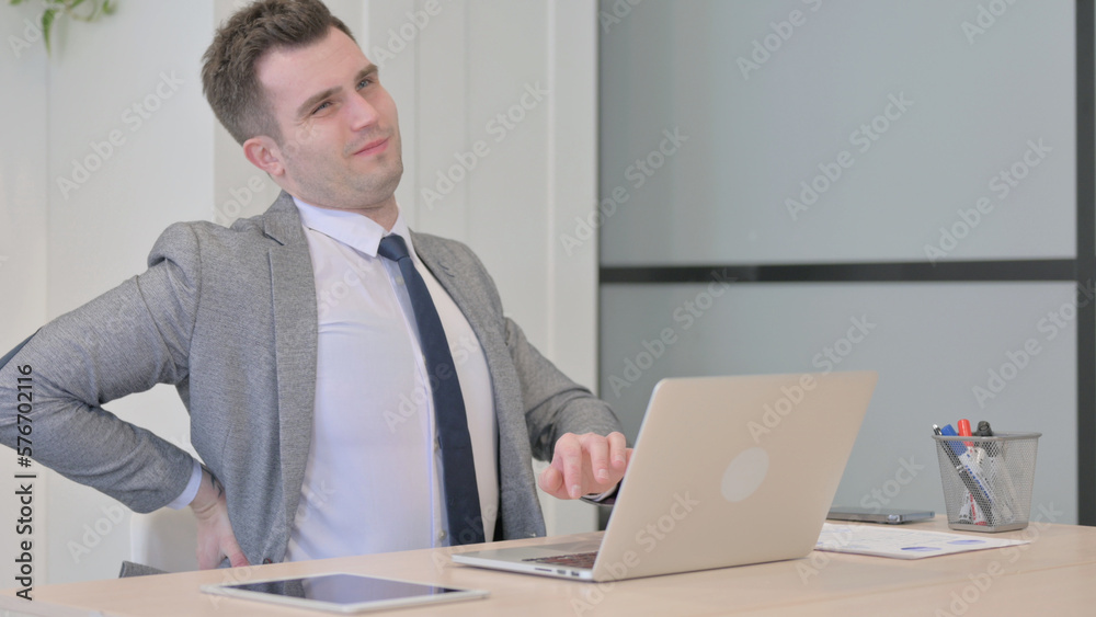 Young Businessman with Back Pain Working on Laptop Young Businessman with Back Pain Working on Laptop