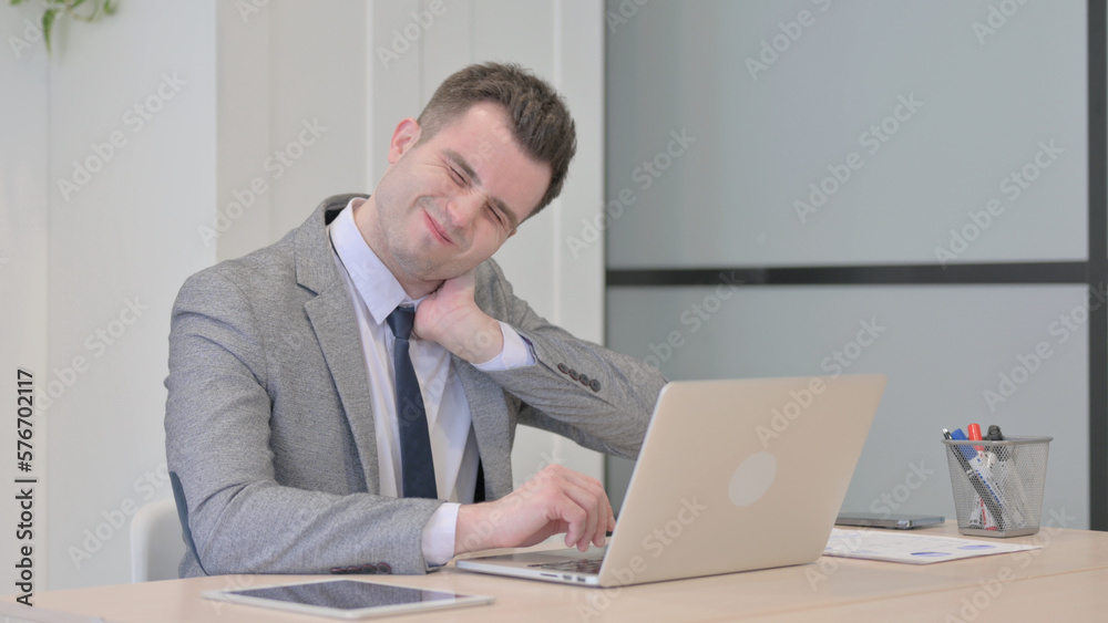 Young Businessman with Neck Pain Working on Laptop Young Businessman with Neck Pain Working on Laptop