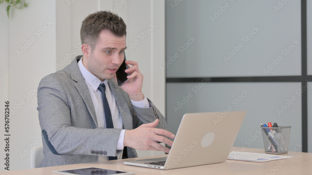 Displeased Young Businessman Talking Angrily on Smartphone at Work Displeased Young Businessman Talking Angrily on Smartphone at Work
