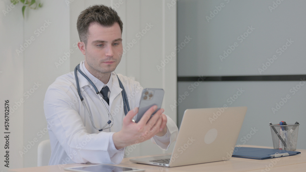 Young Doctor using Smartphone while using Laptop