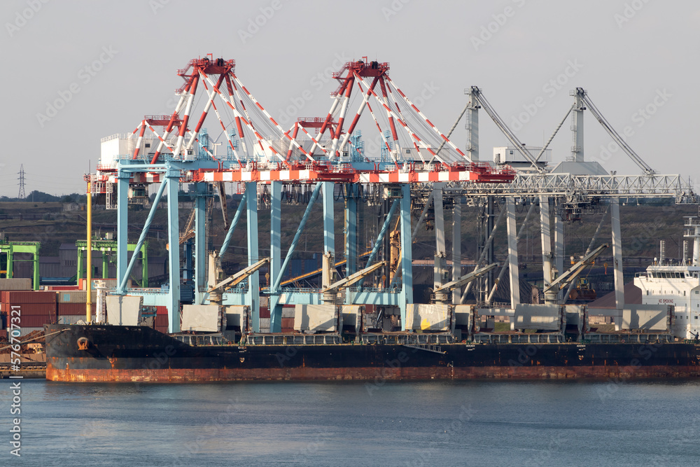 Heaps of coal on Yuzhny seaport. Coal is unloaded from wagons by all kinds of marine cranes onto waste heaps, then loaded into holds of ships. Work is carried out around clock Heaps of coal on Yuzhny seaport. Coal is unloaded from wagons by all kinds of marine cranes onto waste heaps, then loaded into holds of ships. Work is carried out around clock