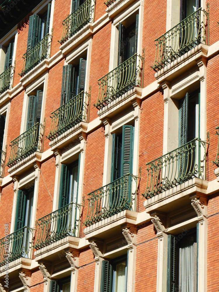 Windows with shutters and small balconies outside on the building facade downtown Madrid, Spain. Vertical photo