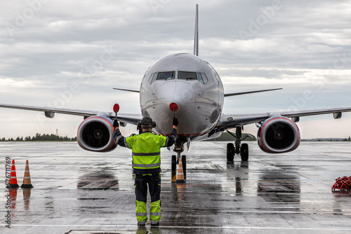 Airplane marshalling at the aiport apron in rainy weather. Passenger aircraft meeting