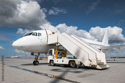 White passenger jetliner with air-stairs on the airport apron