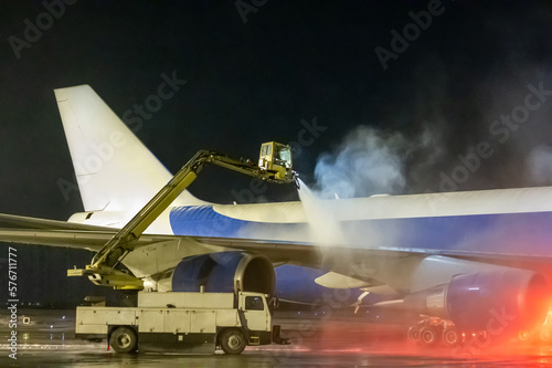 Ground deicing of a big cargo airplane on the night airport apron photo