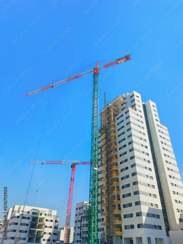 Construction of houses in Israel 2023. Two cranes next to boxes of houses, against a clear sky