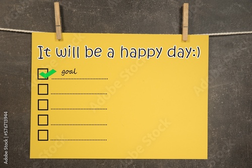 napis "It will be a happy day" na wiszącej żółtek kartce. Koncepcja planowania i realizacji celów.