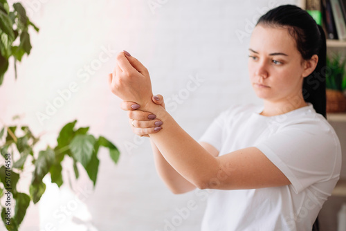 a young girl is holding her wrist in pain at home.