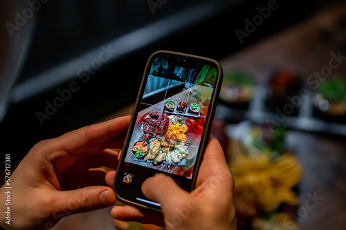 man hand with smartphone photographing food at restaurant or cafe